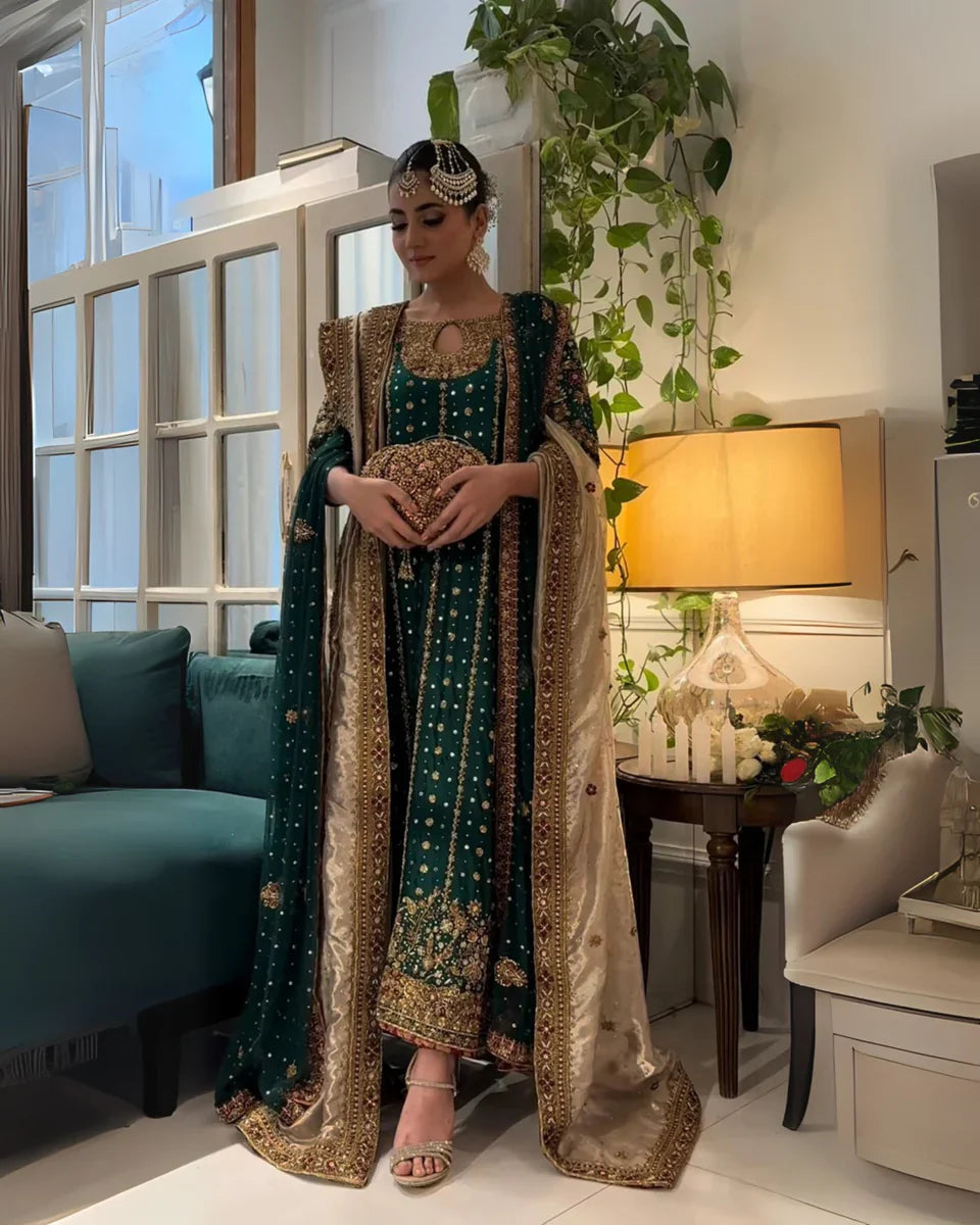 Mehru deep emerald ensemble featuring antique gold and subtle maroon accents with a matching green dupatta edged in ornate red and maroon borders, creating a regal look steeped in timeless tradition and quiet grandeur.