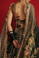 Mohsin Naveed Ranjha Gul-e-Khaas dark green Indian silk lehenga choli featuring a floral printed sleeveless choli with golden embroidery along the neckline and straps, paired with a lehenga layered with appliqués, block-printed motifs, gota patti, mirror work, hand embroidery, and spade-inspired geometric patterns with an ornate golden threadwork hemline, complete with an organza dupatta blooming with printed florals, gota patti, adda work, embroidered borders, kiran trims, and delicate tassels, perfect for