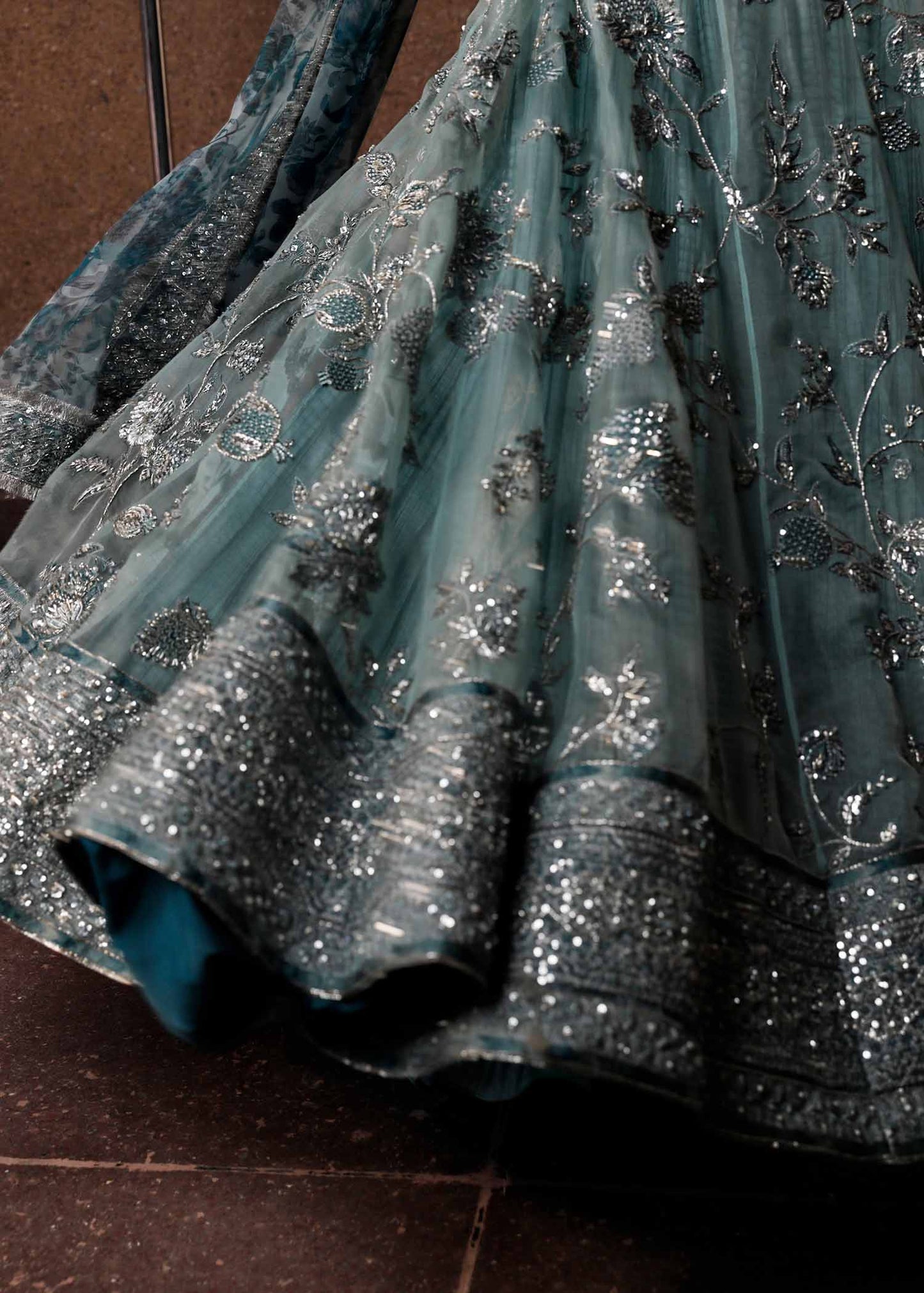  Hussain Rehar Astra ice-blue organza peshwas featuring intricate embellishments on the front and back bodice with heavy embellished borders, paired with a resplendent silk crushed sharara and a digital printed organza dupatta with celestial motifs and four-sided embellished border, perfect for weddings and formal celebrations.
