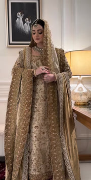 Haris Shakeel Mahrani ivory-gold bridal ensemble featuring a long heavily embellished shirt with intricate handwork including zardozi, dabka, naqshi, and delicate sequin detailing forming graceful floral and traditional motifs, paired with a magnificently worked dupatta with dense borders and finely finished edges, perfect for bridal wear with statement jewelry and traditional headpiece.