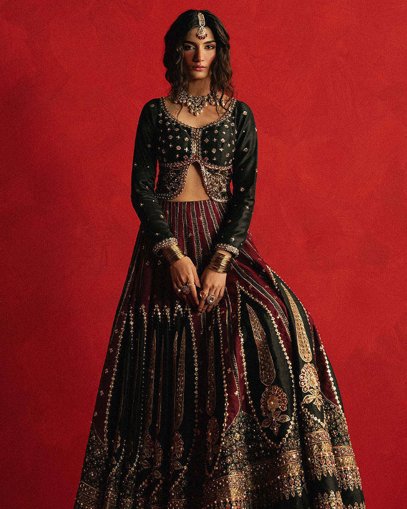 Mohsin Naveed Ranjha Dil Raas black Indian silk lehenga choli featuring a full-sleeved choli with metallic and silk thread embroidery in star-like patterns, paired with a lehenga in deep maroon fading to black with embroidered cypress trees, palmette motifs, mirrorwork, sequins, and golden thread detailing, finished with maroon and gold layered borders, complete with a lightweight organza dupatta featuring maroon and gold floral sprays, gota pati, and adda work, perfect for bridal wear and formal celebratio