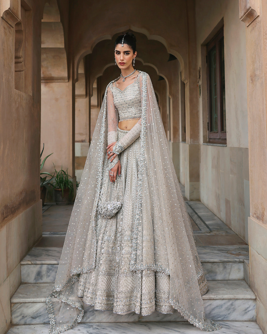 Faiza Saqlain Cammi soft ivory ensemble featuring intricately handworked detailing and delicate embellishments on a flowing silhouette, paired with a sheer dupatta, perfect for weddings and formal occasions.