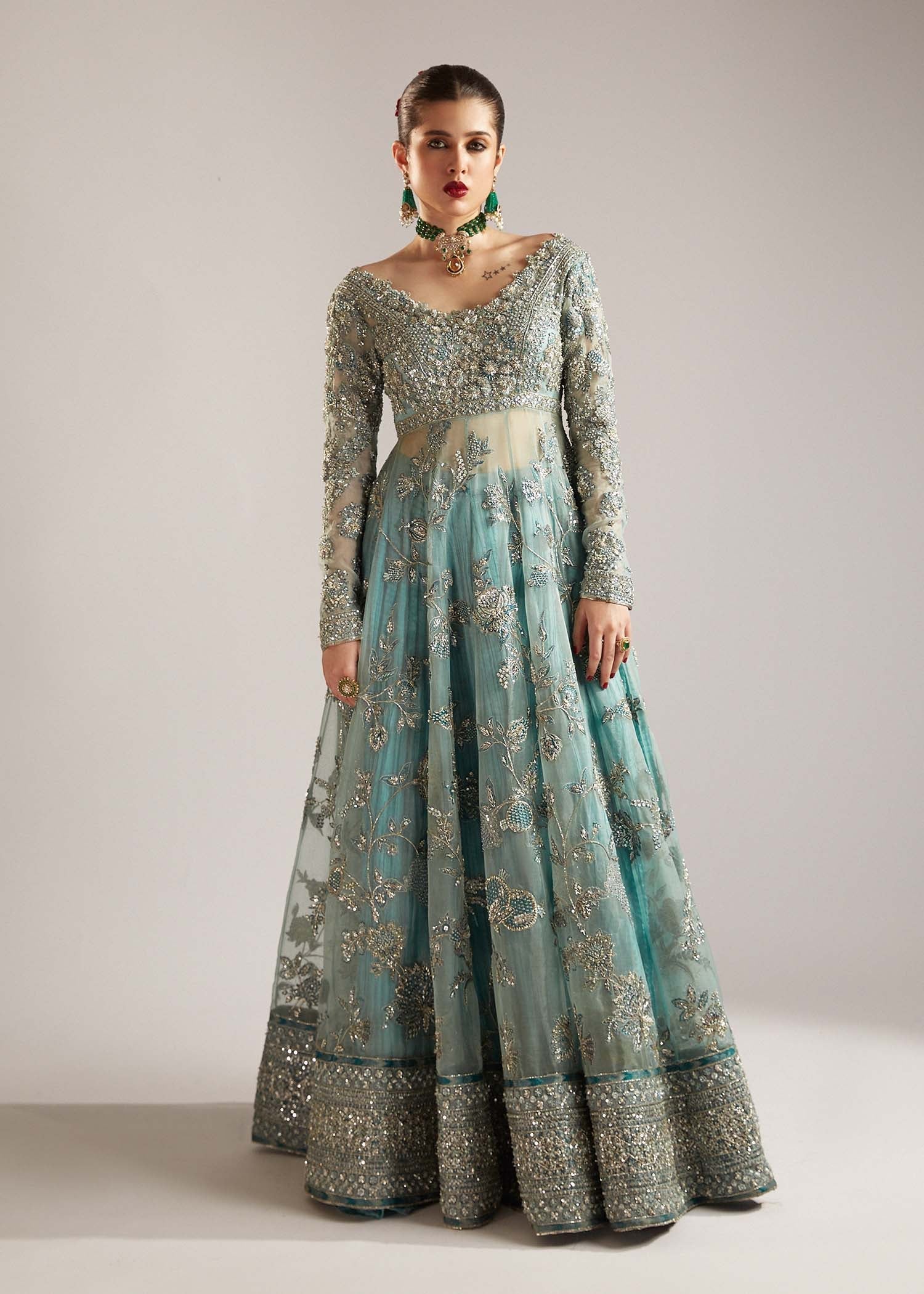  Hussain Rehar Astra ice-blue organza peshwas featuring intricate embellishments on the front and back bodice with heavy embellished borders, paired with a resplendent silk crushed sharara and a digital printed organza dupatta with celestial motifs and four-sided embellished border, perfect for weddings and formal celebrations.


