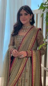  Haris Shakeel pistachio green lehenga choli featuring intricate gold embroidery, delicate hand embellishments, fine zari, sequins, and detailed floral motifs on a soft pastel base, paired with a full-sleeved embellished choli and a sheer net dupatta with rich gold detailing and a contrasting deep pink border, perfect for nikah, engagement, walima, and formal wedding events.