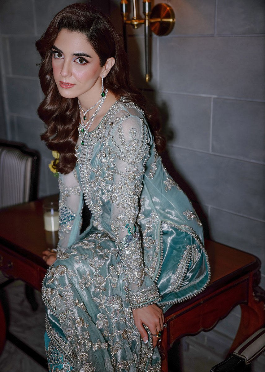 Sara Rohale Asghar Ferozeah aqua long shirt featuring intricate silver embellishments with hand-embroidered floral motifs creating a refined jal, paired with a sheer dupatta with heavily embellished border and scattered sequins, and straight-cut azar trousers with bejeweled peacock hem in silver threadwork, perfect for formal occasions and statement looks.
